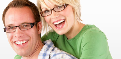 A smiling couple both wearing glasses