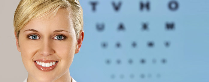 A woman smiling in front of an eye test chart